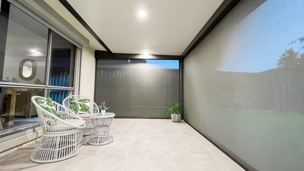 An image showcasing an attached insulated patio roof featuring installed Zipscreen blinds and down lights at the back of a house