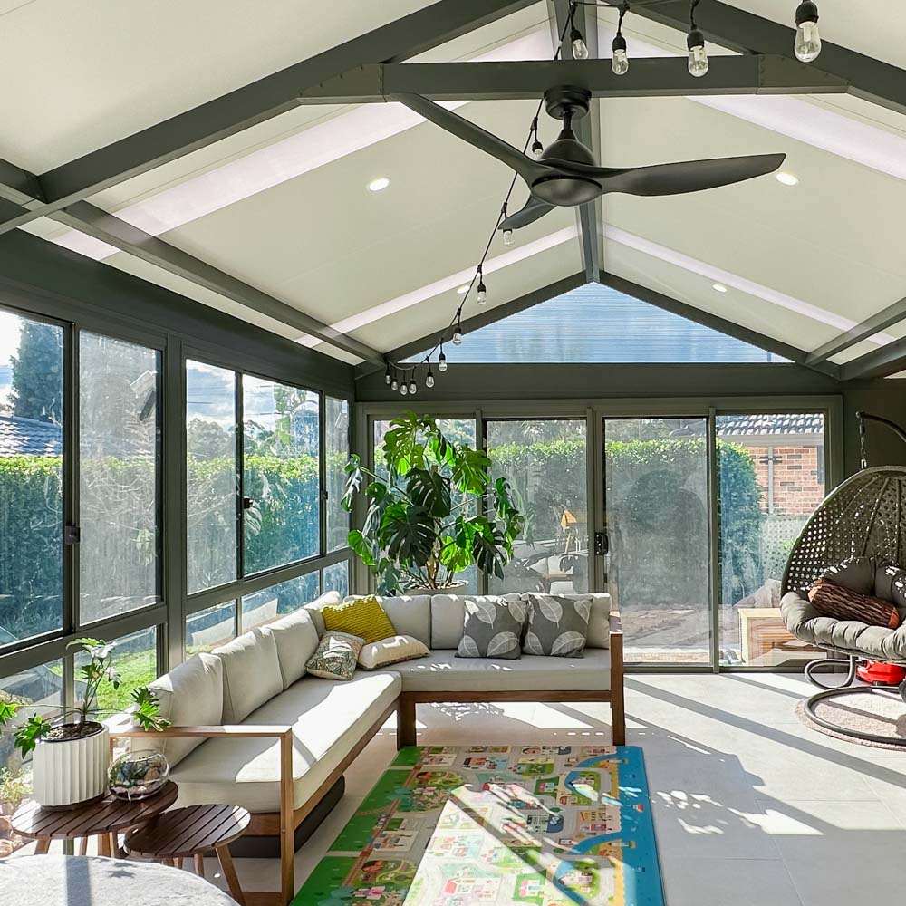 Beautiful sunroom featuring down lights, a ceiling fan, and modern furnishings by Sydney Patios