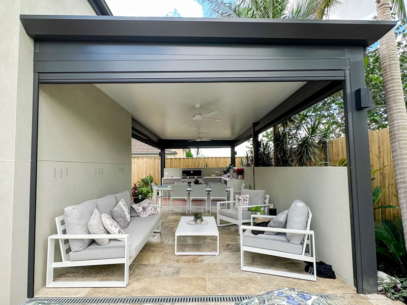 Stylish outdoor living area with an insulated patio awning, Versiclad roofing, Stratco Edge Gutters, Zipscreen outdoor blinds and modern furnishings by Sydney Patios